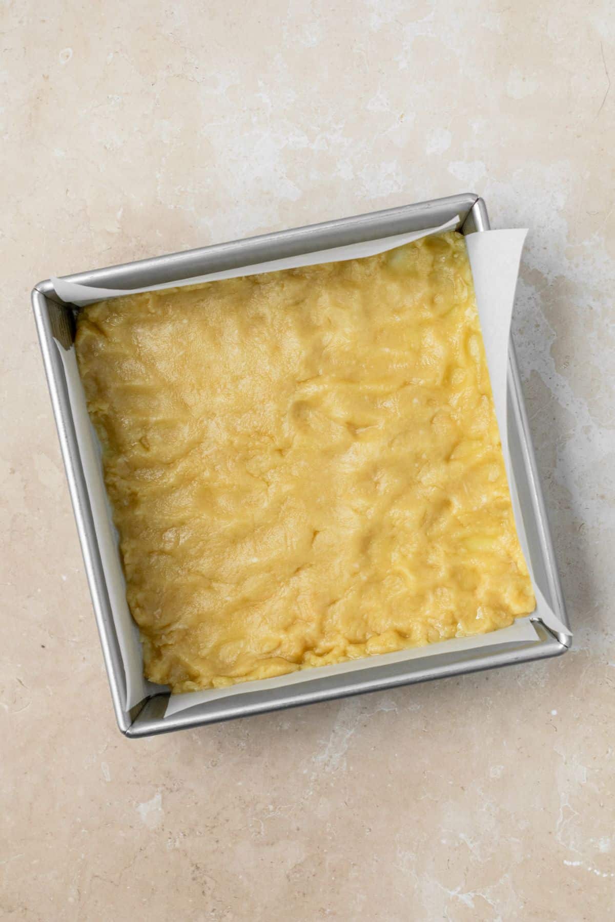 Shortbread crust pressed into a parchment paper lined baking pan.