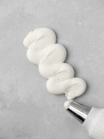 Whipped cream frosting being piped from a piping bag.