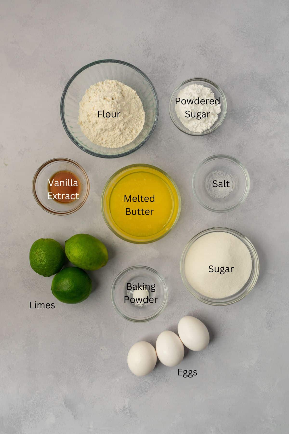 Ingredients for lime bars: flour, powdered sugar, vanilla, butter, salt, limes, eggs, and sugar.