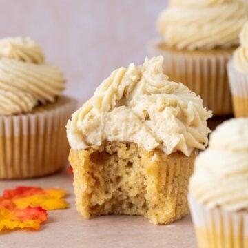Maple cupcake topped with brown sugar frosting. A bite is taken out of one cupcake.