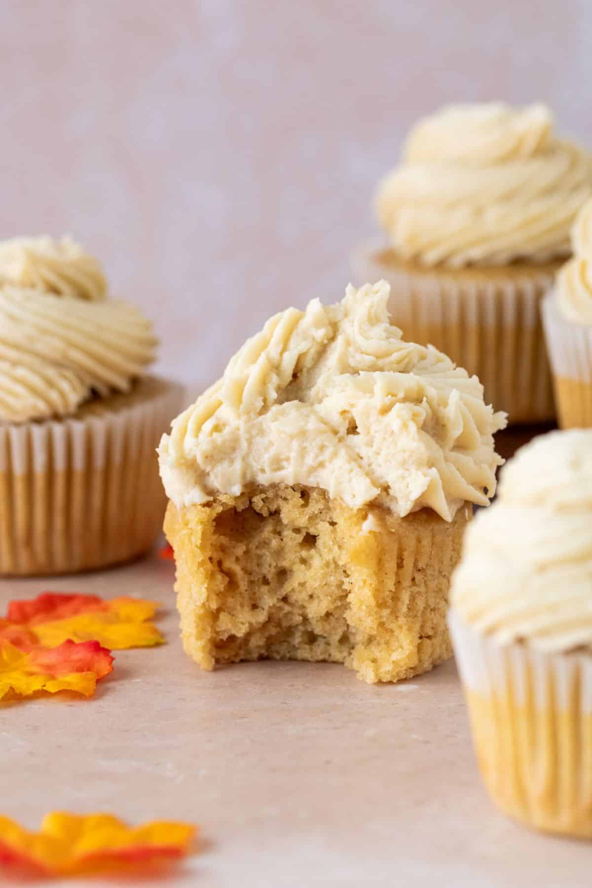 Maple cupcake topped with brown sugar frosting. A bite is taken out of one cupcake.