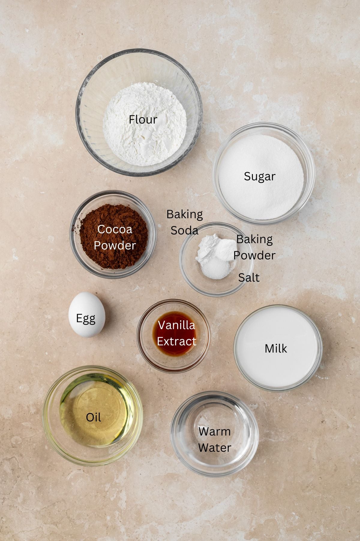 Ingredients for chocolate cupcakes: flour, cocoa powder, baking soda, baking powder, salt, oil, vanilla, sugar, water, and egg.