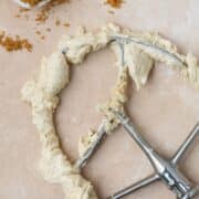 Brown sugar buttercream on a paddle attachment with brown sugar in a small bowl.