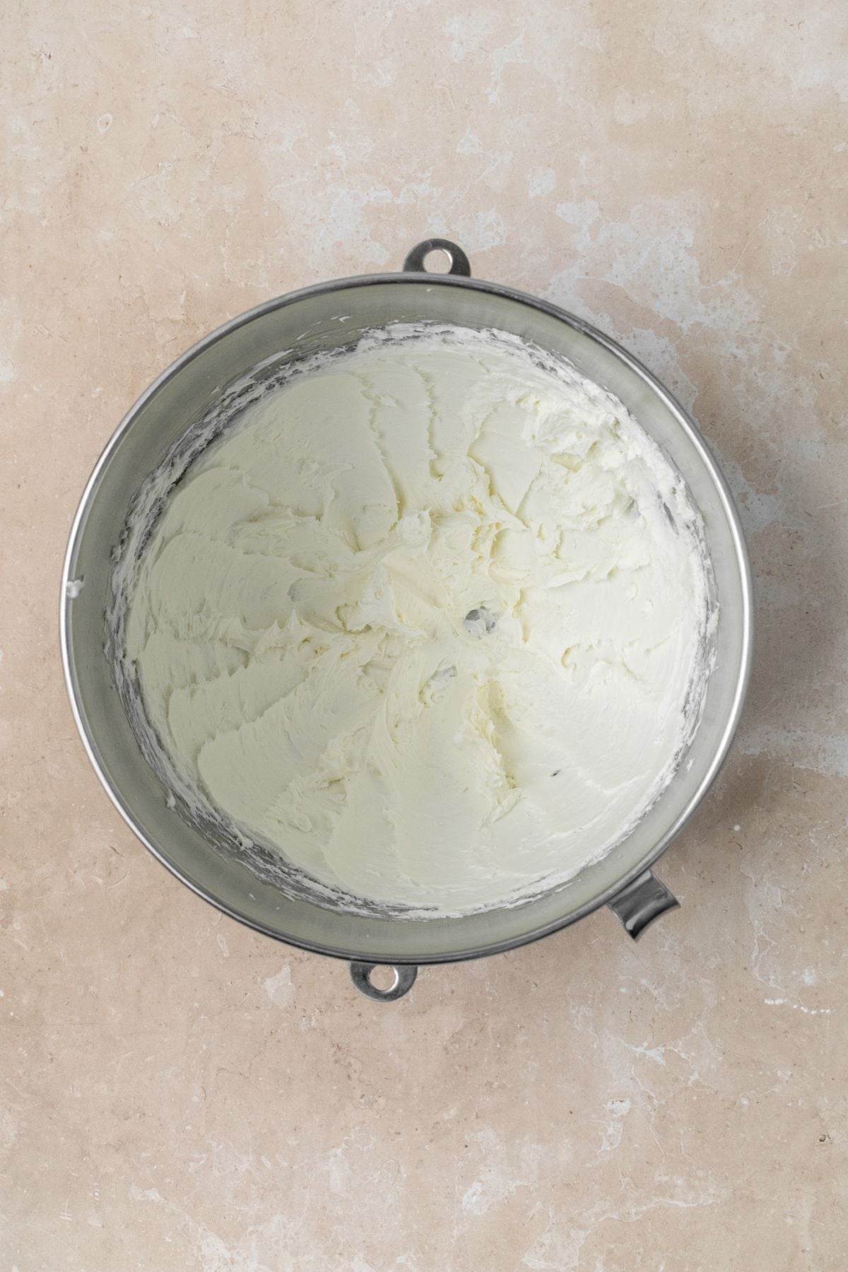 Cream cheese and butter whipped together in a stainless steel bowl.
