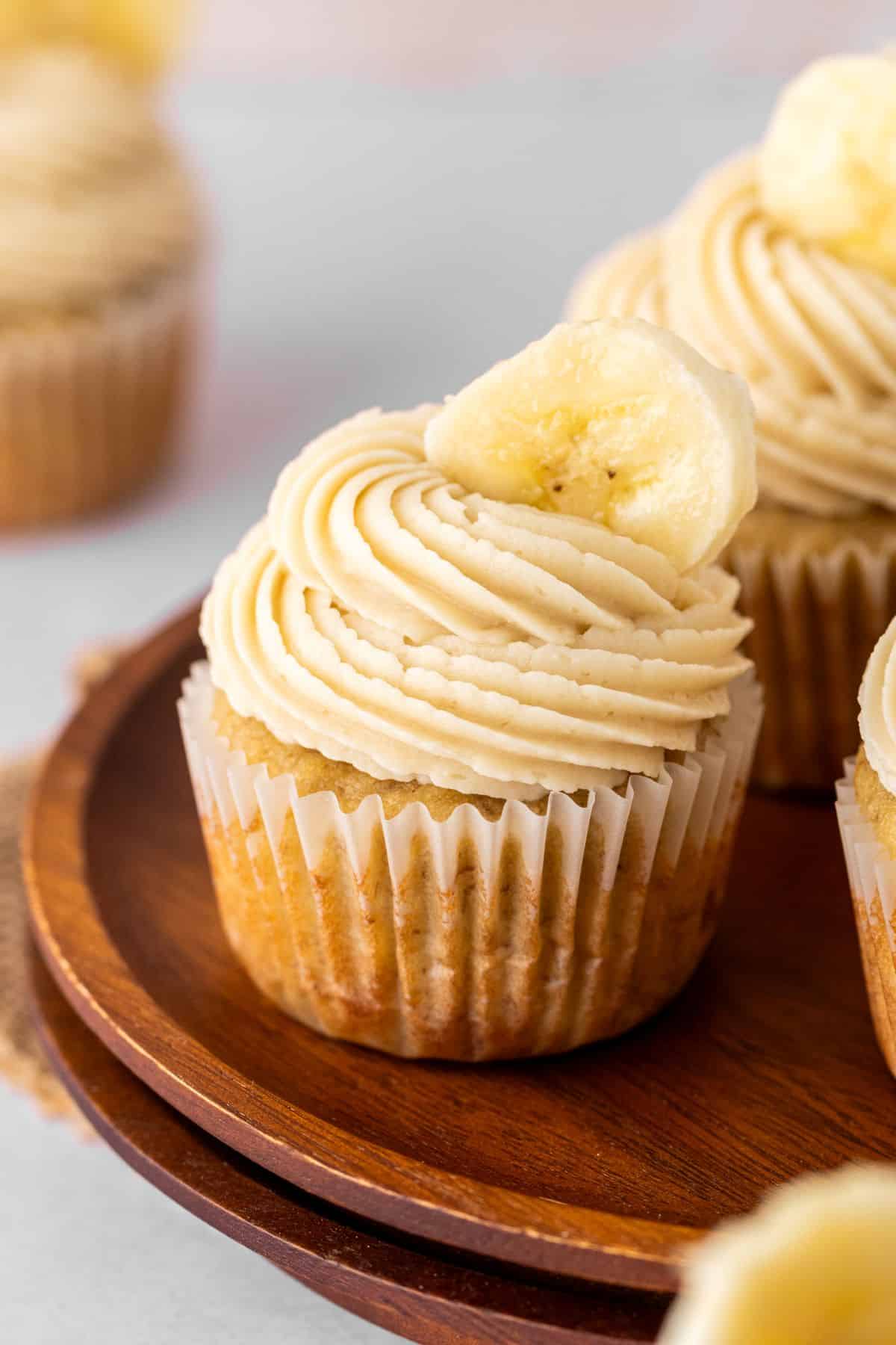 Homemade banana cupcakes topped with frosting and fresh bananas.