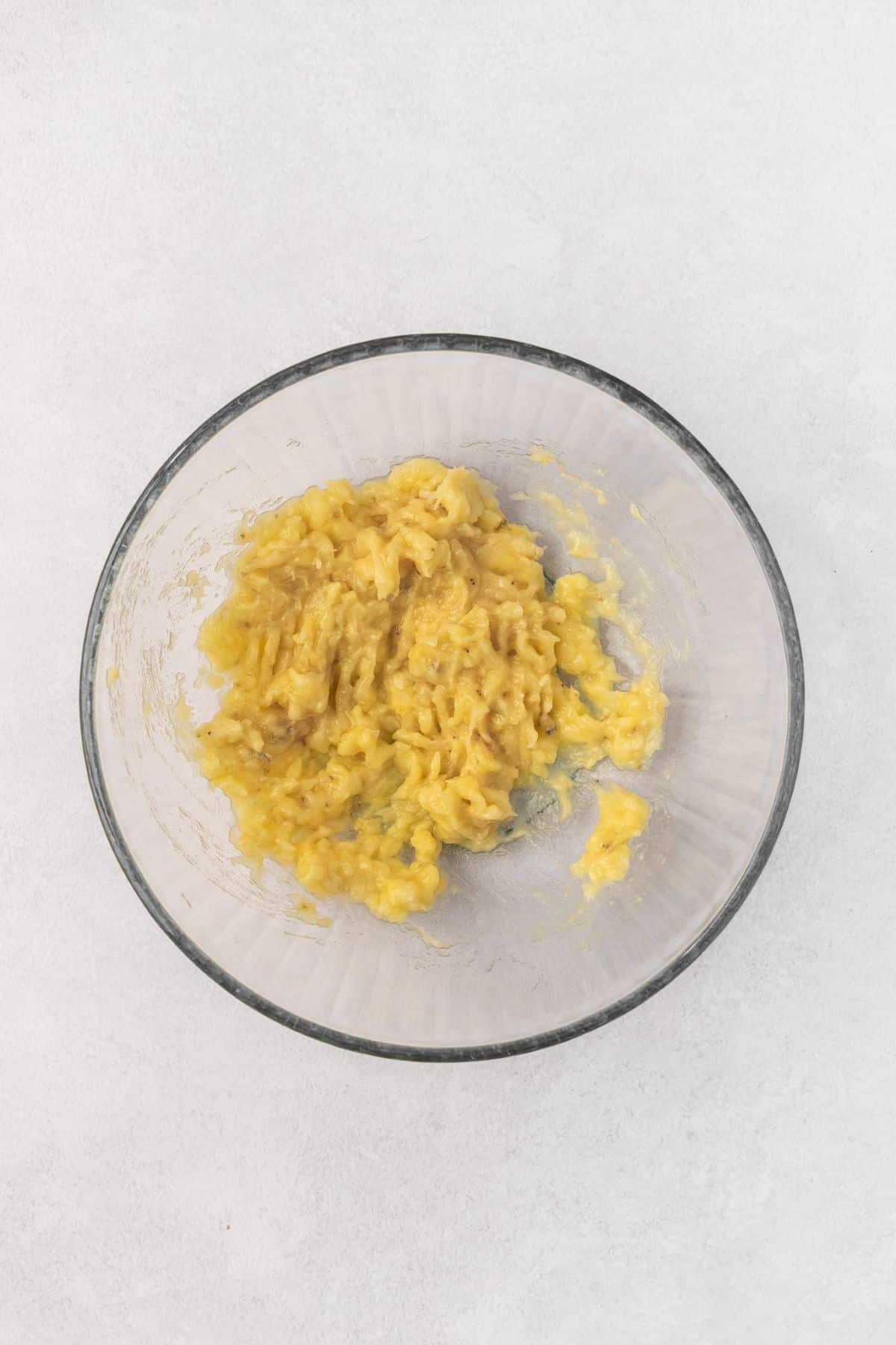 Two mashed bananas in a glass bowl.