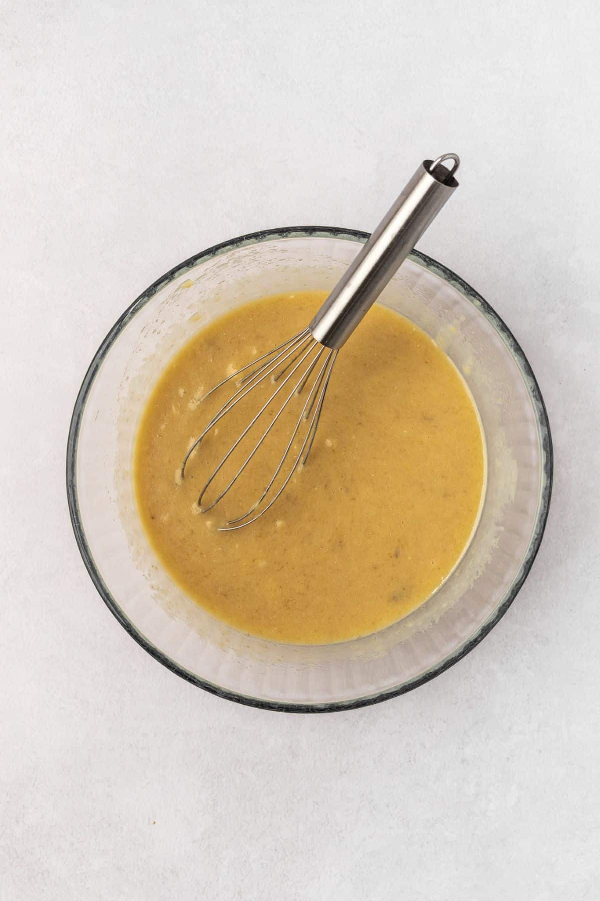 Wet ingredients mixed into the mashed banana bowl.