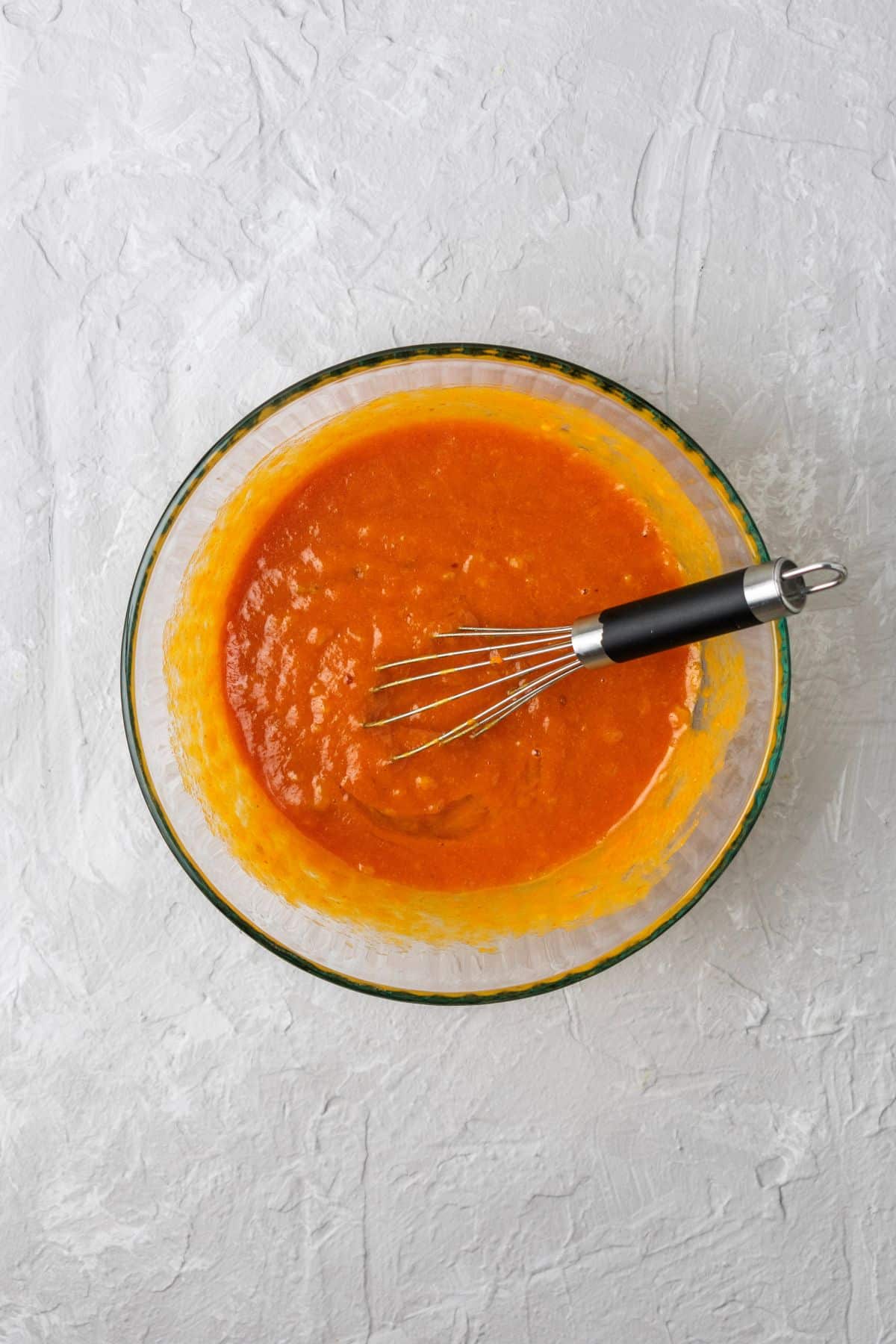 Wet ingredients added to a mixing bowl for pumpkin bread.