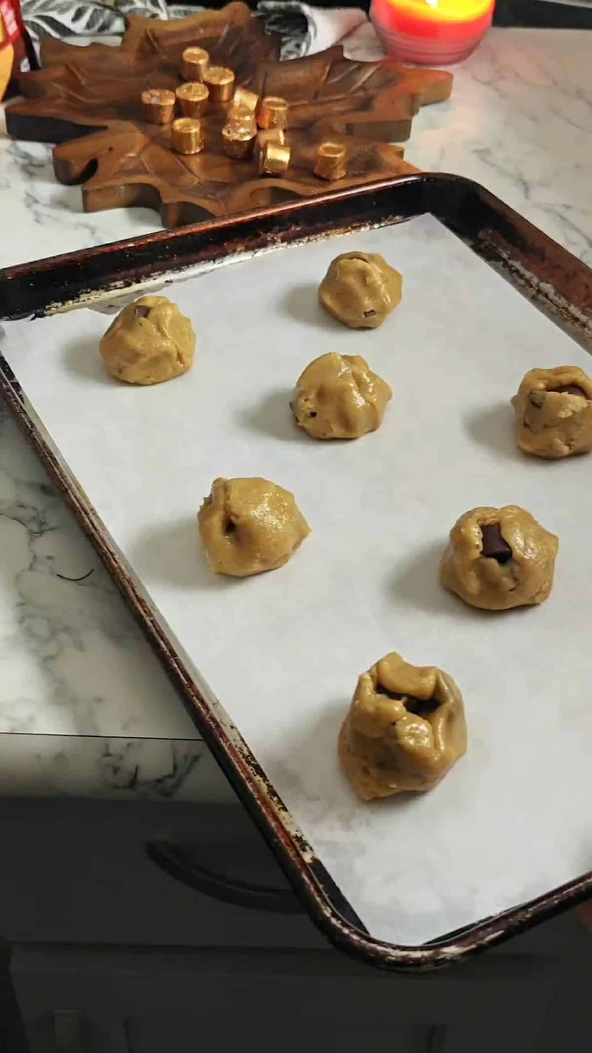 Rolo cookie dough balls on a parchment paper lined baking sheet ready to bake.