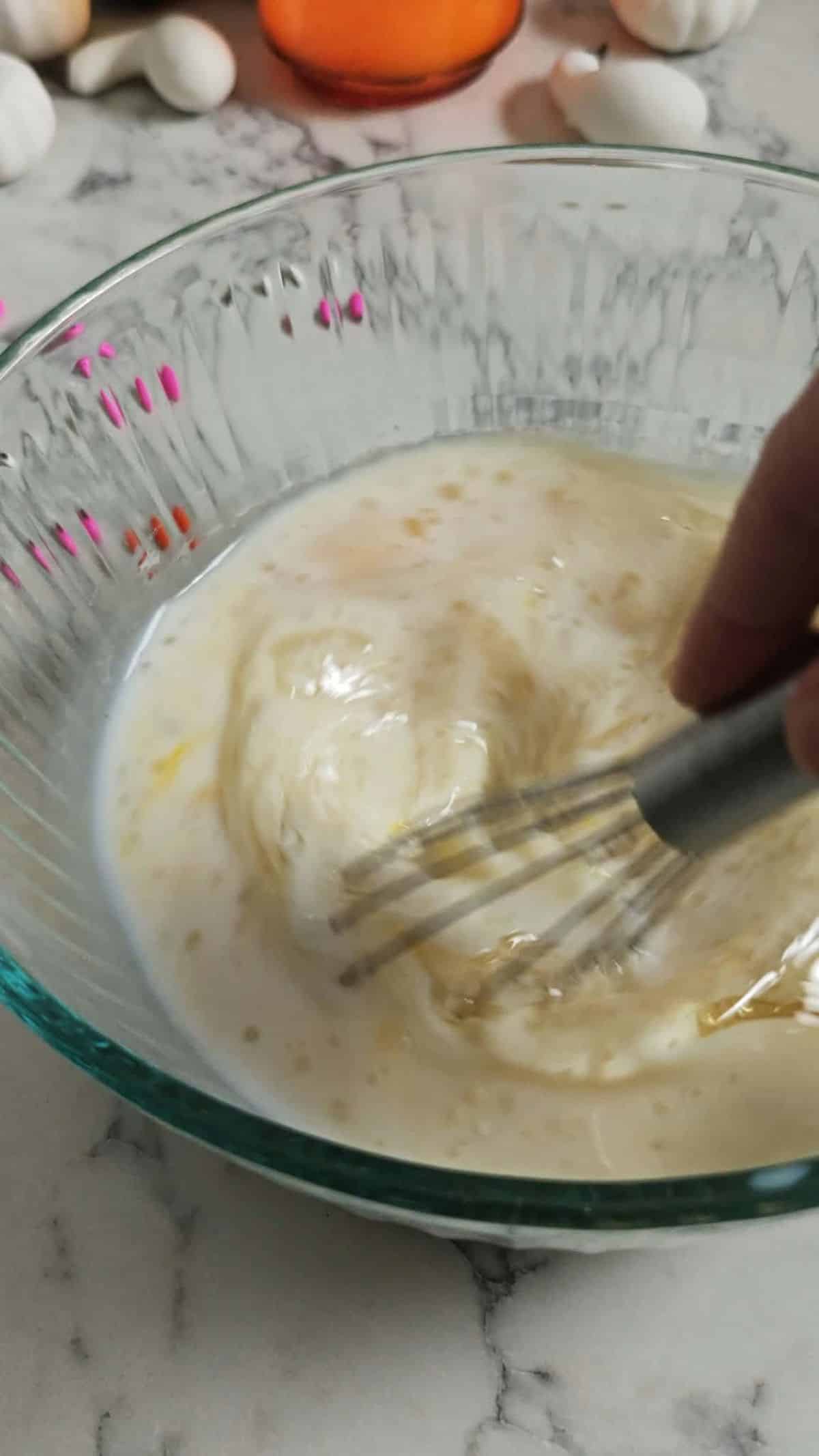 Wet ingredients whisked together in a glass bowl for Halloween cake.
